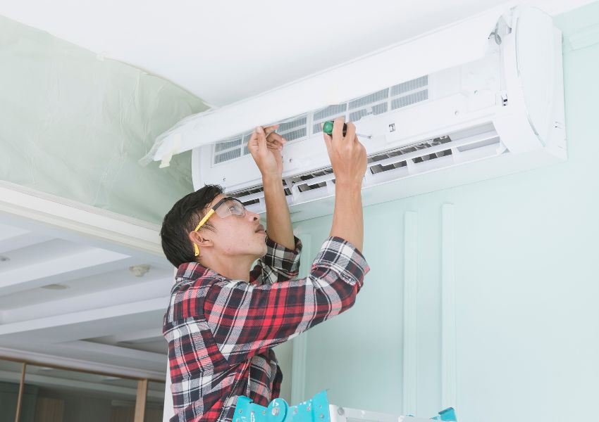 home inspector using a tool to fix part of an air conditioning unit
